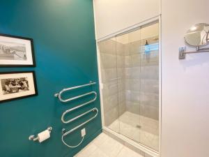 a shower in a bathroom with a blue wall at Delamore Cove - Kauri - Stay Waiheke in Matiatia Bay