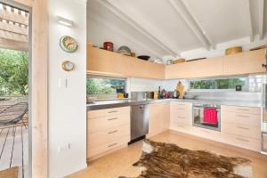 een keuken met witte kasten en roestvrijstalen apparaten bij Palm Views - Stay Waiheke in Palm Beach