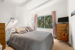 een slaapkamer met een bed en een gitaar erin bij Palm Views - Stay Waiheke in Palm Beach