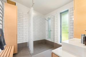 een badkamer met een douche en een wastafel bij Palm Views - Stay Waiheke in Palm Beach +17 foto's