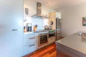 uma cozinha com armários brancos e eletrodomésticos de aço inoxidável em The Sands Apartment 23 - Stay Waiheke em Onetangi