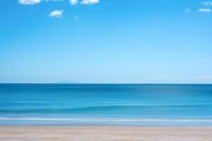 a beach with the ocean in the background at The Sands - Villa 28 - Stay Waiheke in Onetangi