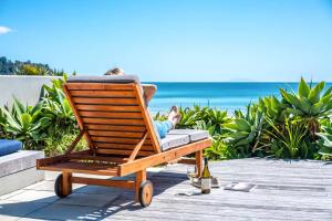 a person sitting in a rocking chair on the beach at The Sands - Villa 28 - Stay Waiheke in Onetangi