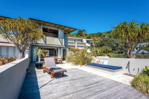 an outdoor patio with a bench and a house at The Sands - Villa 28 - Stay Waiheke in Onetangi