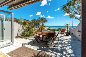 a patio with a table and chairs and the ocean at The Sands - Villa 28 - Stay Waiheke in Onetangi +29 photos