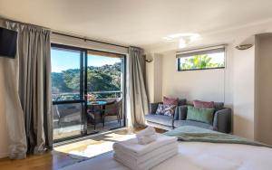 a bedroom with a bed and a couch and a large window at Aqua Sands #1 - Stay Waiheke in Oneroa