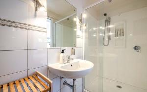 a white bathroom with a sink and a shower at Aqua Sands #1 - Stay Waiheke in Oneroa