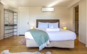a bedroom with a large white bed with a green blanket at Aqua Sands #1 - Stay Waiheke in Oneroa