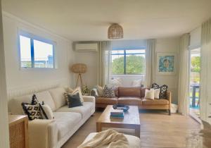 a living room with two couches and a table at Bach 14 - Stay Waiheke in Blackpool