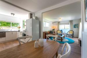 a kitchen and living room with a wooden table and chairs at Bach 14 - Stay Waiheke in Blackpool +16 photos