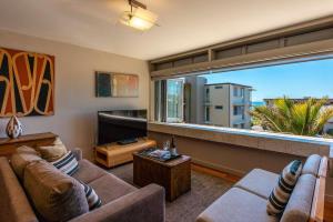 a living room with two couches and a large window at The Sands - Apartment 12 - Stay Waiheke in Onetangi