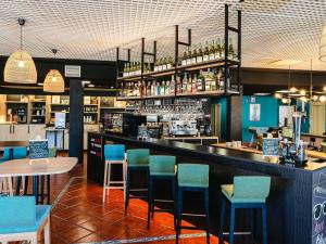 Un bar con sillas azules en un restaurante. en Ibis Jerez De La Frontera Cadiz, en Jerez de la Frontera