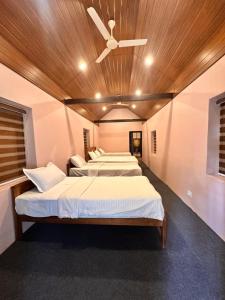 two beds in a room with a ceiling fan at Bucolic Resort in Panamaram +22 photos