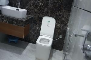 a bathroom with a white toilet and a sink at Meg's Homestay in Jairāmpura