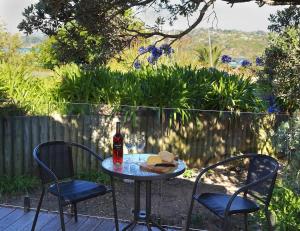 a table with two chairs and a bottle of wine at Tutiri in Oneroa - Stay Waiheke in Oneroa