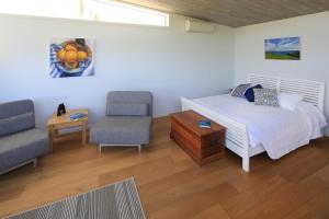 a bedroom with a bed and two chairs and a table at Tutiri in Oneroa - Stay Waiheke in Oneroa