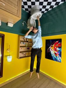 Ein Mann hält in einem Zimmer einen Deckenventilator. in der Unterkunft Như Ba Farmstay in Kon Rung (1)