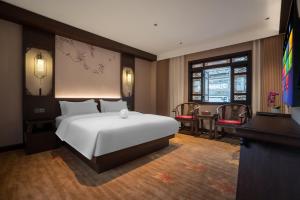 1 dormitorio con 1 cama blanca, mesa y sillas en Lijiang Wangfu Hotel, en Lijiang