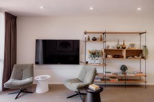 a living room with two chairs and a flat screen tv at Heart of Hobart | CBD Apartment & Parking in Hobart