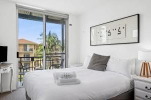 Paradiso Resort by Kingscliff Accommodation في كينغسكليف: غرفة نوم مع سرير أبيض كبير وشرفة