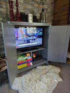a entertainment center with a tv and a white rug at Mountain Cabin With Views Of Bonsenås in Tuddal