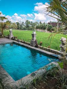 een zwembad in een tuin met een grasveld bij Kemala Hospitality in Tegalalang