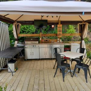 an outdoor kitchen with a table and chairs on a deck at Wainui bush retreat in Kaeo