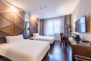 een hotelkamer met twee bedden, een bureau en een televisie bij Orange Hotel Hangzhou Wenyi West Road in Hangzhou