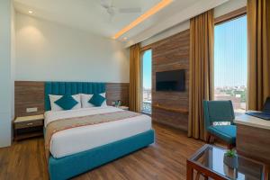 a bedroom with a bed and a desk and a tv at Hotel SG Continental Amritsar !! Prime Location ! Parking ! Open Terrace in Amritsar