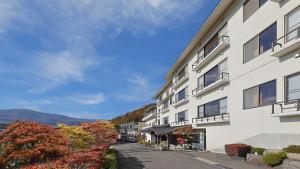 かっぱの宿旅館三治郎 في Zao: مبنى ابيض كبير فيه اشجار وجبال في الخلف