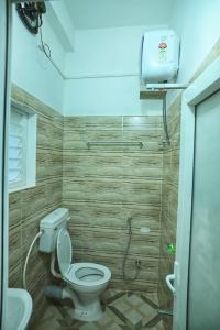 a bathroom with a toilet and a sink and a light at Hotel Tricon Residency in Guwahati +6 photos
