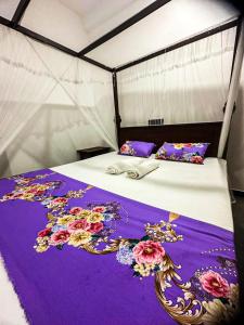 Una cama con sábanas moradas y flores. en Lyra Mirissa, en Mirissa 2 fotos más