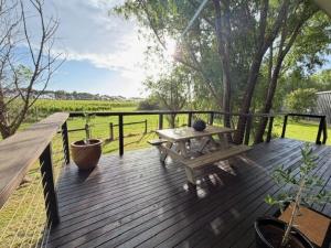 een houten terras met een bank en een tafel bij Vineyard Cottage at Oakdene in Wallington