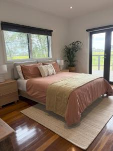 een slaapkamer met een groot bed en een groot raam bij Vineyard Cottage at Oakdene in Wallington