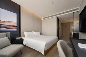 ein Schlafzimmer mit einem weißen Bett und zwei Stühlen in der Unterkunft 上海静安寺西康路亚朵酒店 in Shanghai