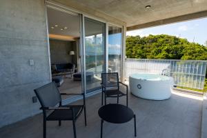 a bathroom with a tub and chairs on a balcony at Emerald Ocean Villa in Onna
