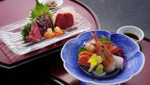 かっぱの宿旅館三治郎 في Zao: طبقين من الطعام على طاولة حمراء