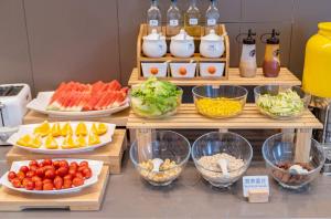 - un buffet composé de assiettes de nourriture et de bols de fruits et légumes dans l'établissement Hanting Hotel Shanghai Jiaotong University Jiangchuan Road Subway Station 2, à Shanghai