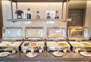 une ligne de buffet avec des plateaux et des assiettes de nourriture dans l'établissement Hanting Hotel Shanghai Jiaotong University Jiangchuan Road Subway Station 2, à Shanghai
