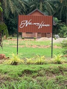 Un cartel de un hotel en medio de un campo. en Nizana House Homestay, en Batu Pahat