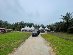 a car driving down a dirt road with white tents at Nizana House Homestay in Batu Pahat
