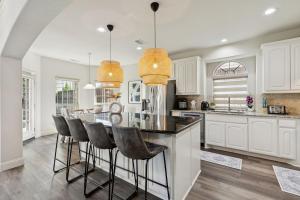una cocina con armarios blancos y una isla con taburetes. en Modern 6BR Luxury Villa - Theater, Games, Peloton & EV, en McKinney