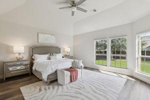 Un dormitorio blanco con una cama y un ventilador de techo. en Modern 6BR Luxury Villa - Theater, Games, Peloton & EV, en McKinney