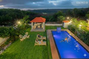 a group of people sitting on chairs next to a swimming pool at Ekostay Cliffside Villa I Mountain View in Lonavala