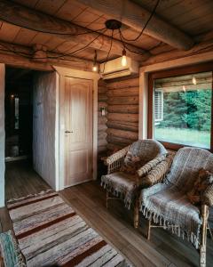 a porch of a log cabin with two chairs and a door at Romantic stay at loghouse VäikeTeeMaja in Üksnurme