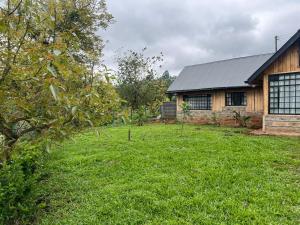 a house with a grass yard next to a building at The T Cottage in Othaya