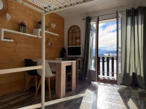 a room with a desk with a computer and a balcony at STUDIO LES JONQUILLES in Les Angles