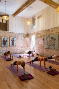 eine Gruppe von Leuten, die in einem Zimmer Yoga machen in der Unterkunft La Manufacture Royale 1739 in Montolieu