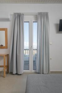 een slaapkamer met gordijnen en een raam met uitzicht bij Vavoulas Village in Mikri Vigla
