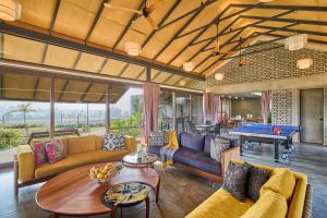 a living room with couches and a pool table at SaffronStays Ashfield - 5BHK Eco-Farmhouse with Pools, Jacuzzi, Lawn & Games Room in Nashik